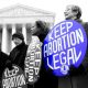 woman holding a sign that says keep abortion legal