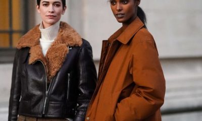 two models in fall jackets stand on a street corner in paris