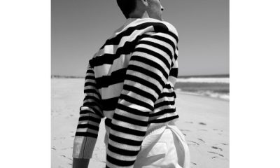 Black and white photo of man wearing striped sweater on beach