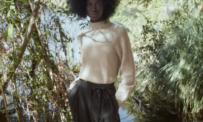 a model wears a reformation cashmere sweater in front of a forest background as part of the reformation 2021 sale