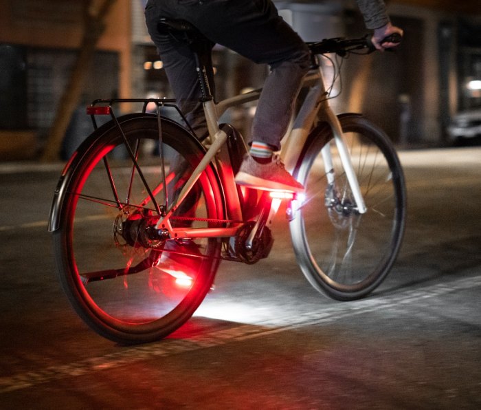 Cyclist riding bike at night with red and white light on pedals