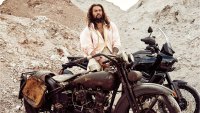 Jason Momoa standing in front of vintage Harley Davidson motorcycles with desert backdrop