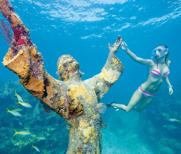 Woman in striped bikini diving among sunken ship