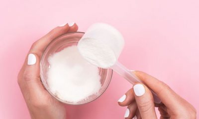woman hands with a scoop with collagen or protein powder and a glass of water trendy beauty supplement for healthy skin and bones flatlay, top view