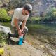 Man inserting filter into purifier bottle by streambed