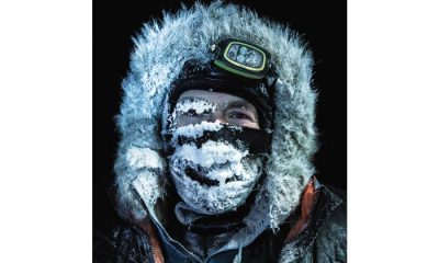 Man wearing fur hood and head lamp with frost covering face