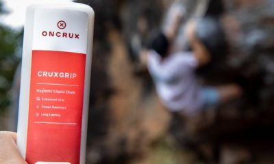OnCrux Cruxgrip liquid chalk in hand with climber in background