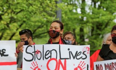 woman with her face painted holding a sign that says stolen lives on stolen lands