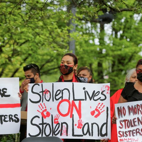 woman with her face painted holding a sign that says stolen lives on stolen lands