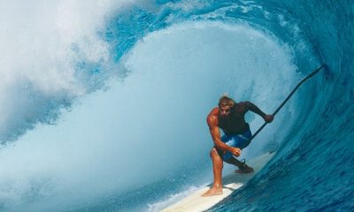 Laird Hamilton riding big wave on paddleboard with paddle