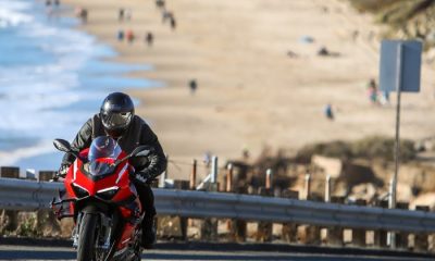 Rider on a 2021 Ducati Superleggera V4 motorcycle, riding up a hill on Pacific Coast Highway with California beach in the background