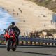 Rider on a 2021 Ducati Superleggera V4 motorcycle, riding up a hill on Pacific Coast Highway with California beach in the background