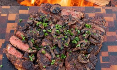 New York Strip Steaks cut up on a wooden cutting board campfire cooking