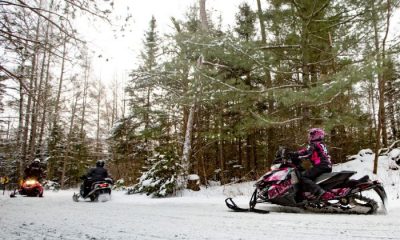 Snowmobile riders on a snowmobile trail through the trees in Eagle River, Wisconsin