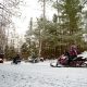 Snowmobile riders on a snowmobile trail through the trees in Eagle River, Wisconsin