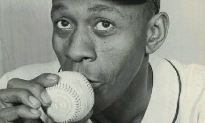 Baseball legend Satchell Paige holds a baseball to his lips.