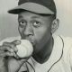 Baseball legend Satchell Paige holds a baseball to his lips.