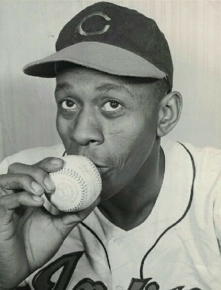 Baseball legend Satchell Paige holds a baseball to his lips.