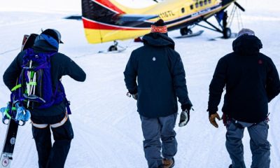 Heli ski guides and clients walk to small yellow airplane