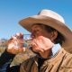 Man in cowboy hat drinking water