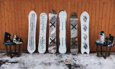Six black and white patterned snowboards leaning against wall