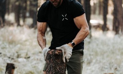 Man wearing black T-shirt chopping wood in gloves