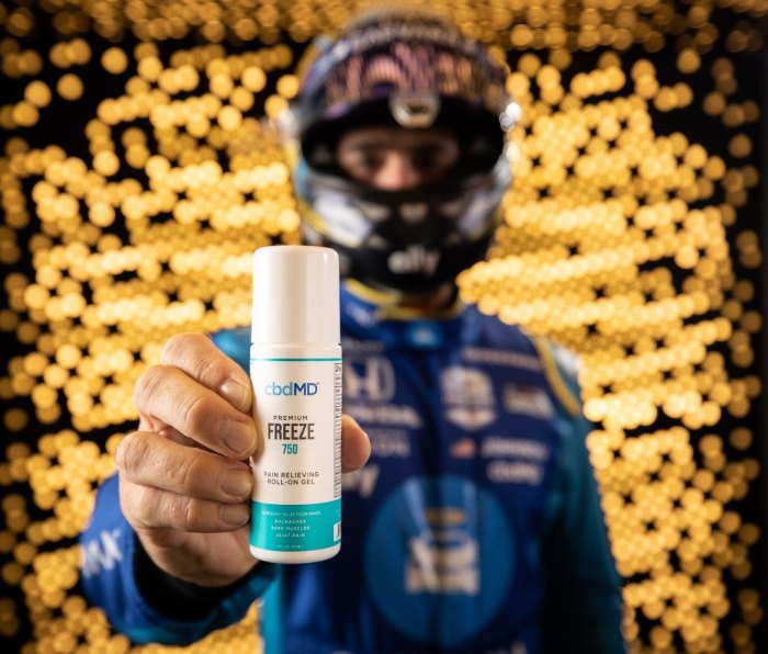 Race car drive holding cbdMD’s Recover Pain Relief Cream