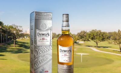 Bottle of "Champions Edition" Dewar's 19 and silver box container with a golf course background
