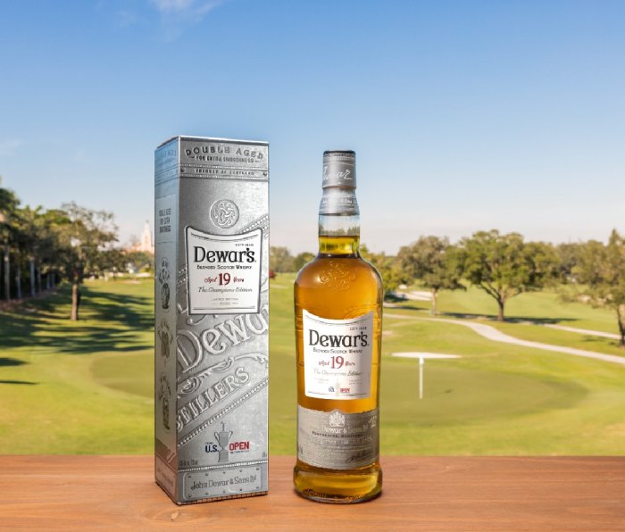 Bottle of "Champions Edition" Dewar's 19 and silver box container with a golf course background