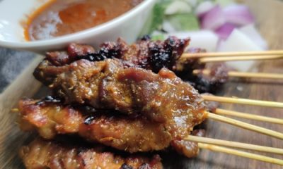 Satay skewers arranged on a plate next to a bowl of dipping sauce. Urban Hawker
