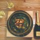 Bottle of Champagne and two filled glasses beside a plate of black cod and saikyo miso rice