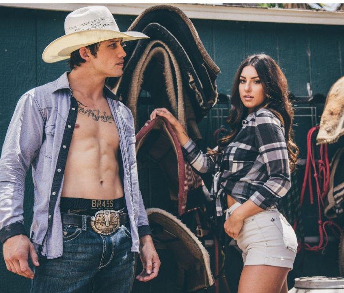 Bonner Bolton stand in the saddle room in cowboy hat and open shirt. Girl stands beside him.
