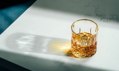 Glass of whiskey in sunlight on white tabletop