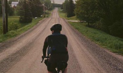 Man riding a bike along a gravel road. new england bikepacking