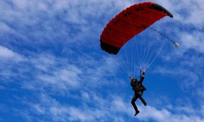 Skydiver floating down to earth with red parachute