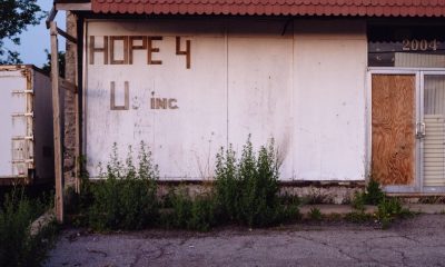 An abandoned building with the words "Hope 4 U inc" on the facade. The doors are boarded up with plywood.